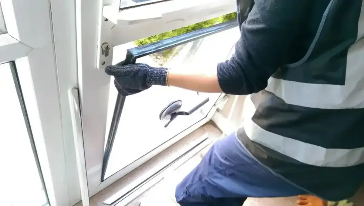 Technicien manipulant l'ouvrant d'un châssis PVC blanc