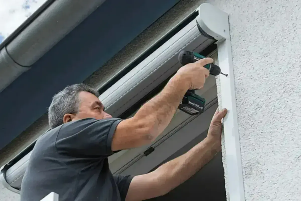 Technicien fixant le coffre d'un volet roulant